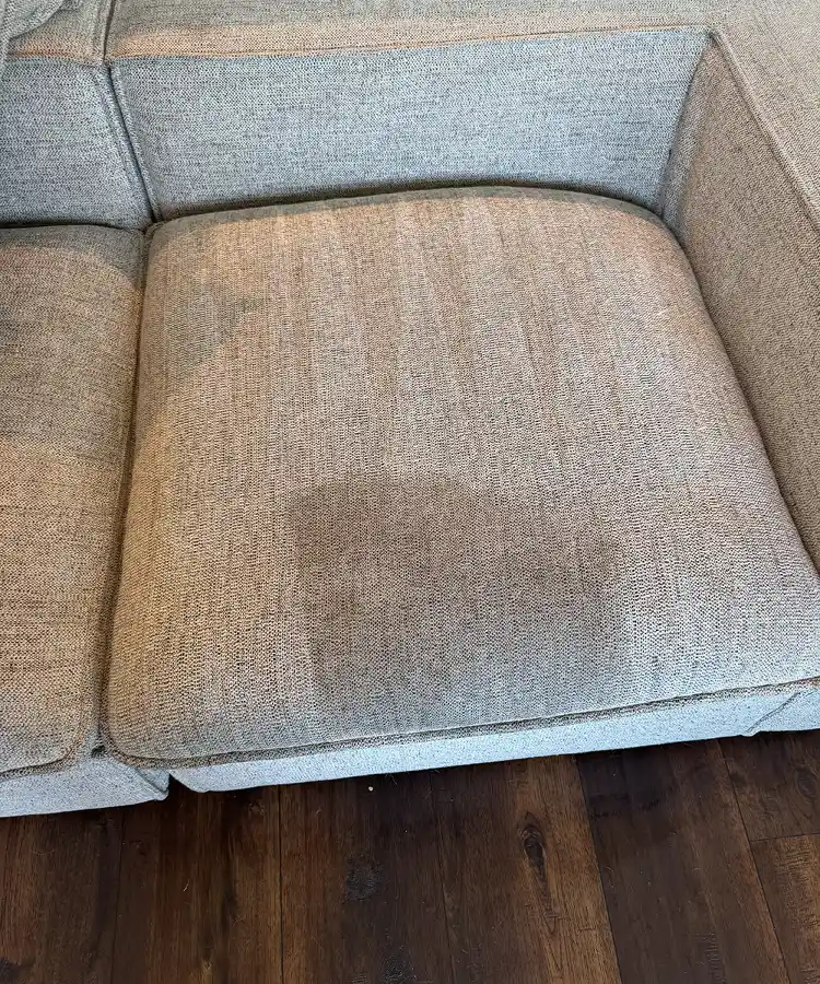 Upholstery Cleaning in Menifee 8 Heavy dark liquid spill spot requiring deep upholstery cleaning in menifee on a grey couch cushion
